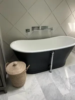 Black freestanding soaking tub with chrome fixtures and marble tile bathroom