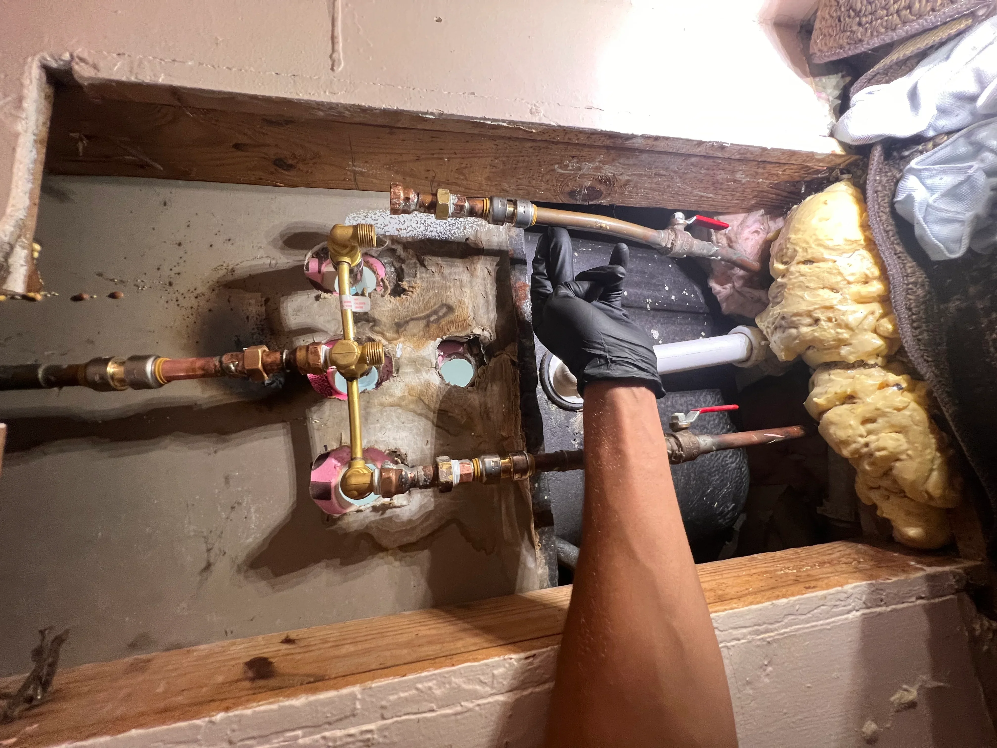 Brass radiant floor heating manifold with zone valves and insulated copper tubing installation