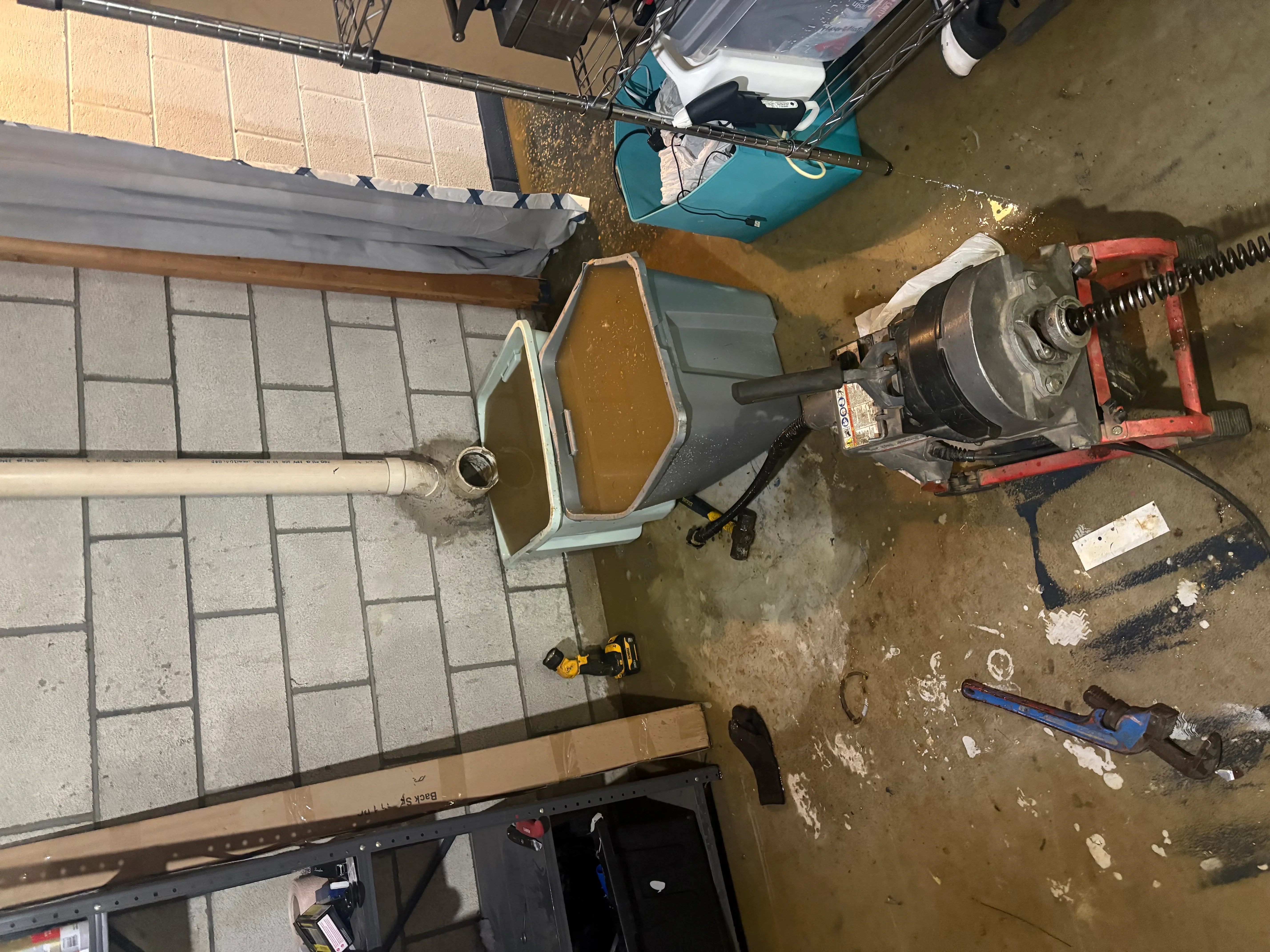 Basement plumbing installation with PVC drains, cast iron pipes, and mechanical equipment