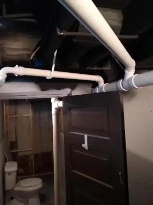 White PVC drain pipes with fittings and brackets installed above bathroom vanity