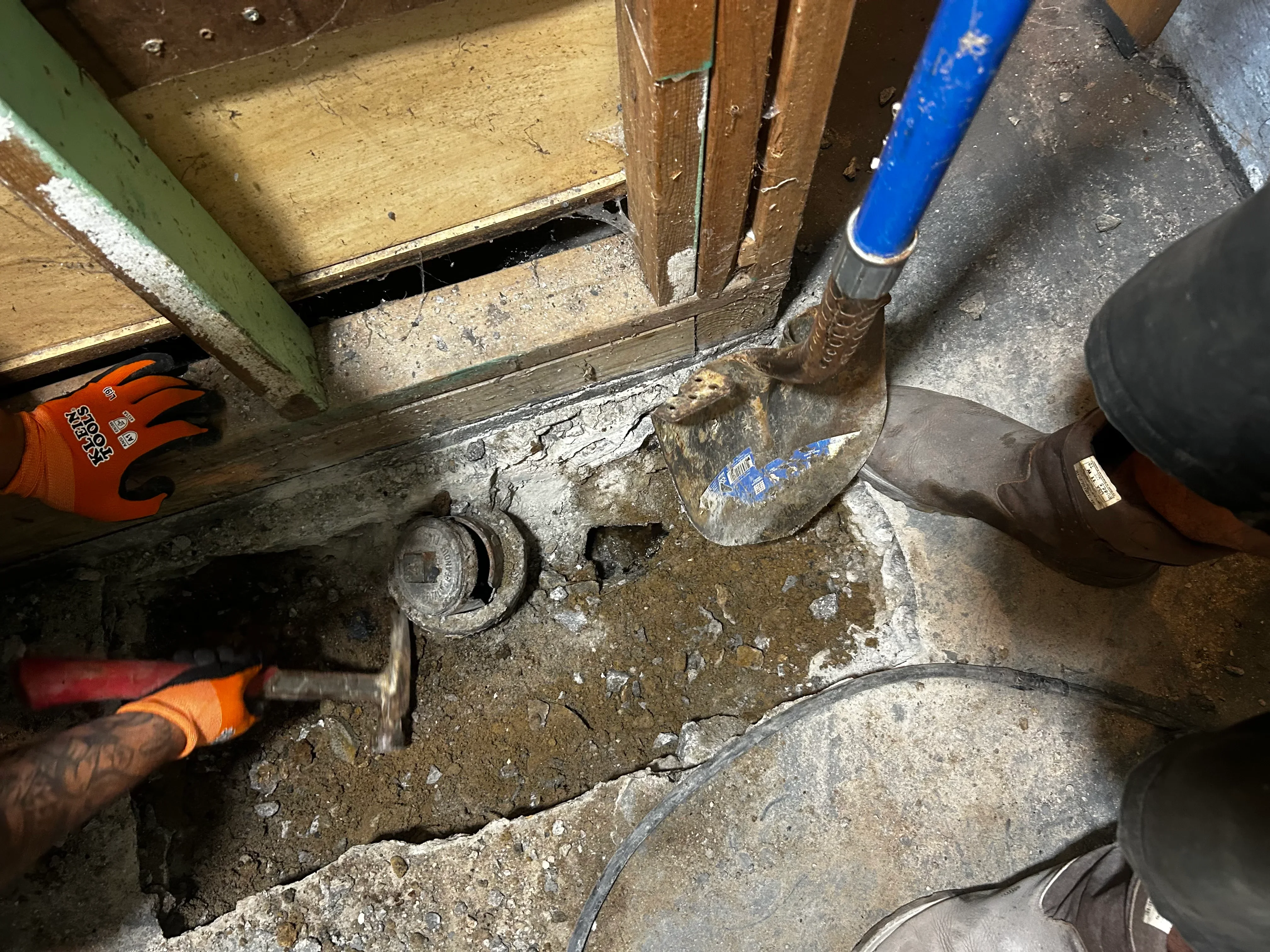 Underground plumbing excavation showing corroded metal pipes and fittings during repair work