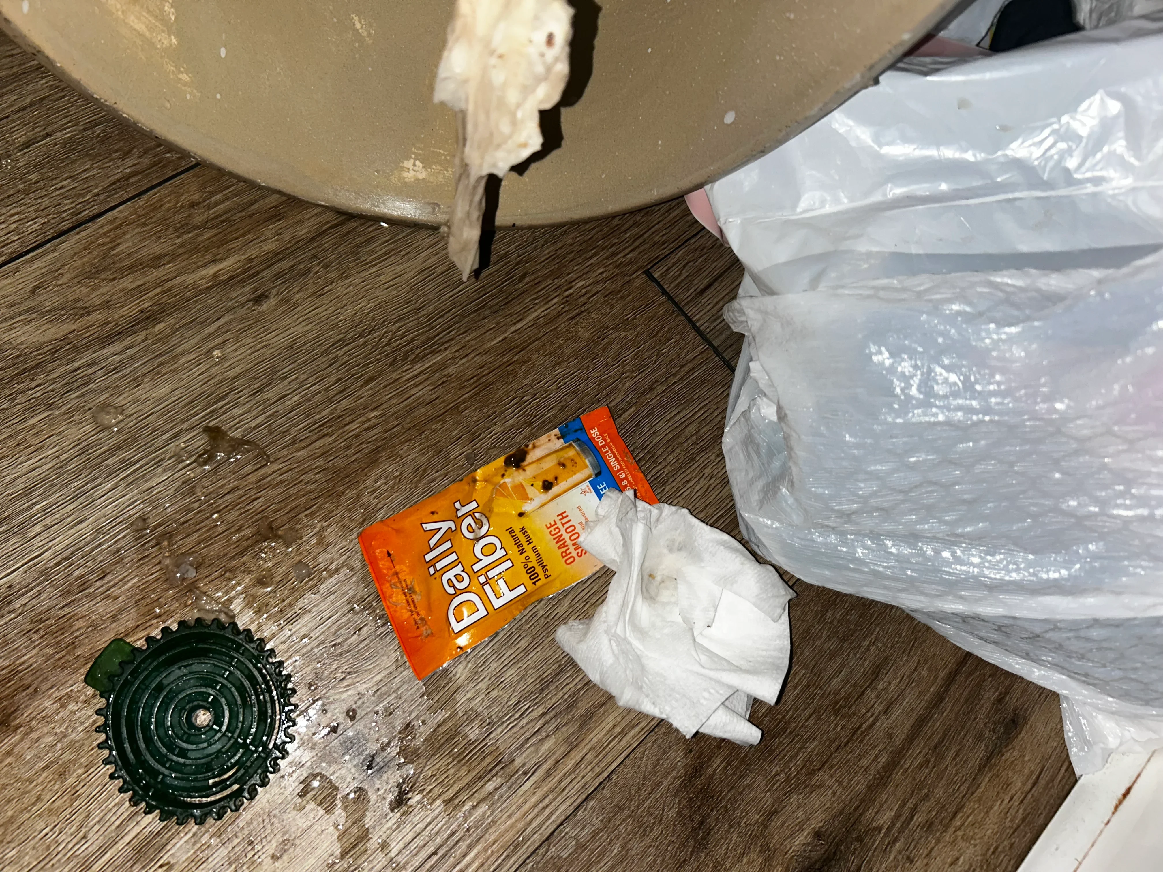 Drywall joint compound, sanding disc, and protective plastic sheeting on wood-look flooring