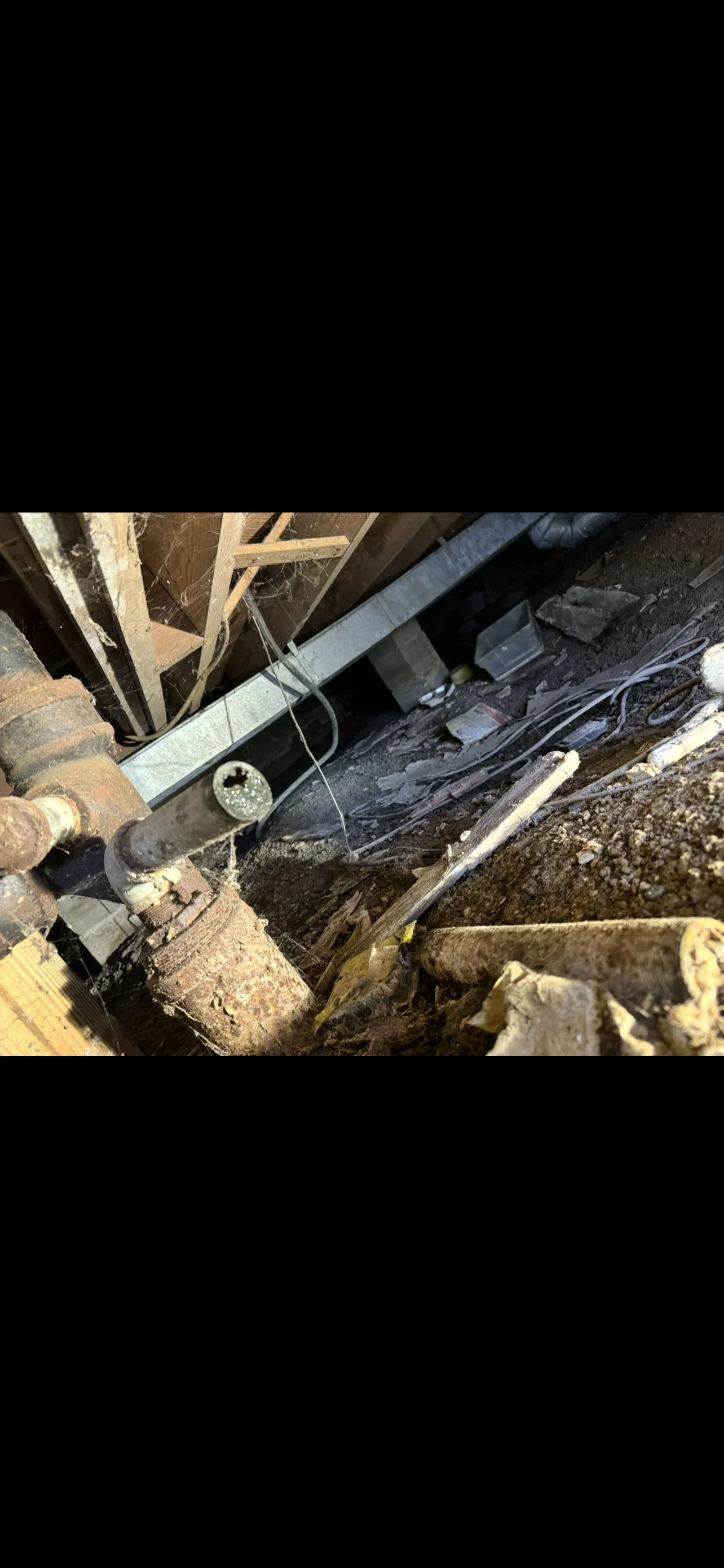 Underground drainage pipe installation with metal conduit, strapping, and gravel foundation