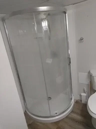 Curved glass shower enclosure with chrome frame and door in white bathroom