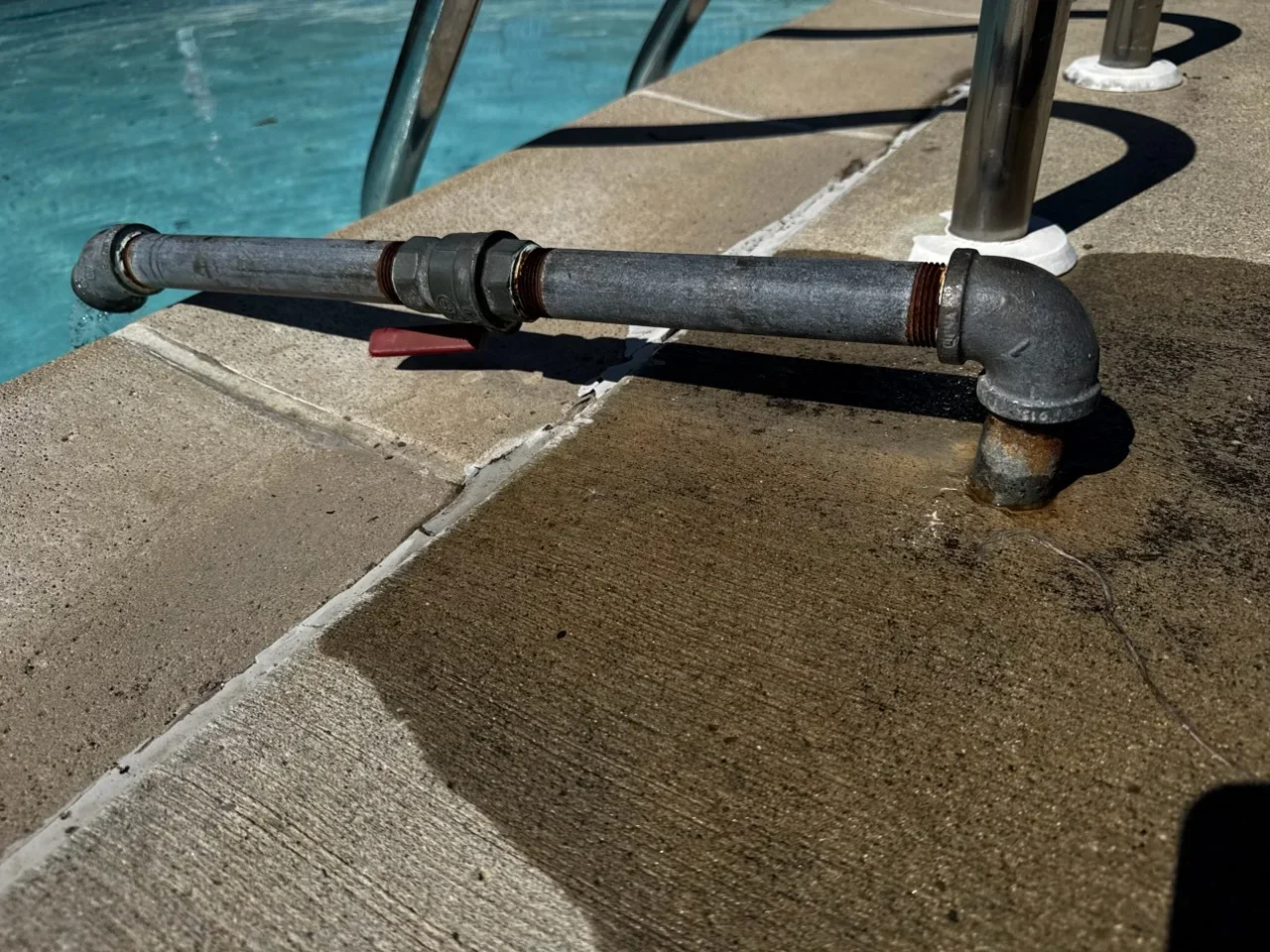 Cast iron drain pipe with threaded fittings and elbow installed at pool deck