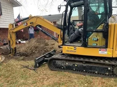 CAT mini excavator with operator performing septic system site excavation and soil management