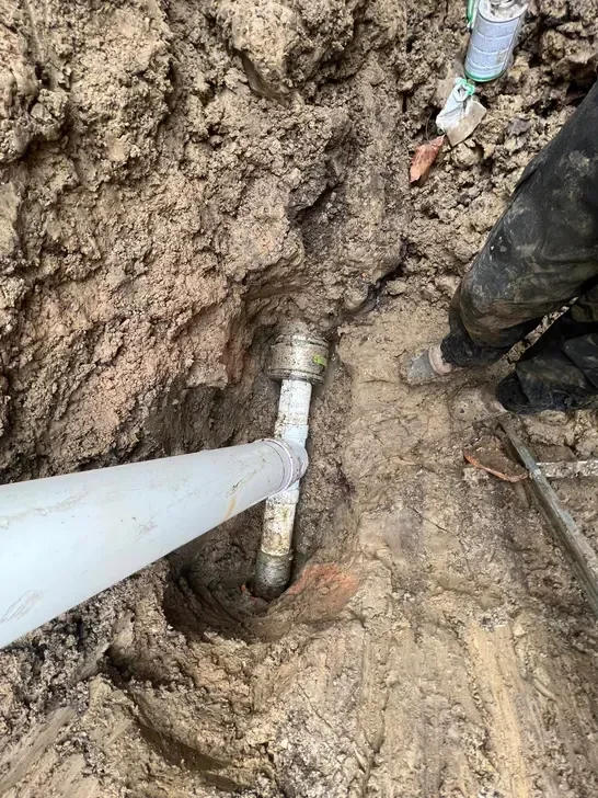 White PVC sewer pipe installed in excavated trench with soil backfill